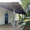 Veranda con tettoia, sedie bianche e tavolo al lato di una casa bianca.