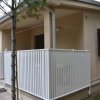 Casa beige con veranda recintata bianca.