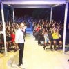 Persona su palco con pubblico entusiasta.