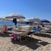 Spiaggia con ombrelloni e lettini blu a righe bianche.