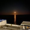 Luna piena sopra il mare con riflessi dorati sull'acqua.
