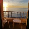 Balcone con sedie bianche che si affaccia su un tramonto sul mare.