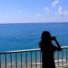 Persona fotografa l'oceano dal balcone.