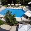 Vista dall'alto di una piscina circondata da lettini e ombrelloni.