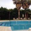 Piscina con lettini e ombrelloni, circondata da palme.