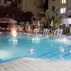 Piscina illuminata di notte con decorazioni galleggianti.