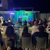 Spettacolo serale all'aperto con pubblico seduto.