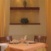 Tavolo apparecchiato per due in una sala con scaffali decorativi e tende arancioni.