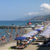 Spiaggia affollata con ombrelloni e bagnanti.