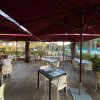 Tavoli apparecchiati all'aperto sotto grandi ombrelloni bordeaux.