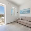 Salotto con divano beige e porta aperta su un terrazzo.