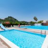 Piscine all'aperto con uno scivolo e sedie a sdraio, cielo sereno.