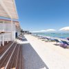 Spiaggia con sedie a sdraio e ombrelloni bianchi, vista mare limpido.