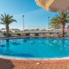 Piscina con palme e lettini sotto un ombrellone.