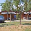 Bungalow di legno tra gli alberi, auto parcheggiata davanti.