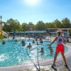 Persone che si divertono in una piscina con struttura per scivoli e animatori.