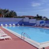 Piscina con lettini, ombrelloni e cielo sereno.
