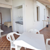 Terrazza con tavolo e sedie bianchi e accesso a una stanza interna.