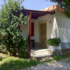 Casa bianca con tetto rosso, ingresso coperto, piante lungo il vialetto.