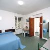 Camera con letto matrimoniale e singolo, scrivania sotto una finestra aperta.