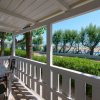 Veranda coperta con tavolo e sedie, vista su alberi e mare.