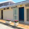 Edificio con ingressi aperti e fioriere sul marciapiede.