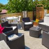 Area salotto su terrazza con poltrone nere, tavoli piccoli e piante decorative.
