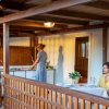 Due persone su una veranda, una cucina e l'altra sieda a tavola.