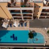 Veduta aerea di una piscina rettangolare con lettini e ombrelloni attorno.