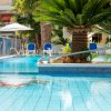 Piscina con palme e lettini blu, in un ambiente soleggiato.