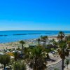 Spiaggia soleggiata con mare blu e palme.