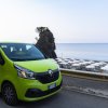 Furgone verde Renault vicino a una spiaggia con ombrelloni bianchi.