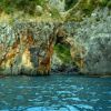 Barchetta vicino a alte scogliere con passaggio naturale.