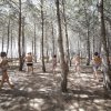 Persone in costume corrono tra alberi in una pineta.