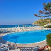 Piscina circolare con vista mare e lettini.