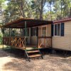 Una casa mobile nel bosco con veranda coperta e gradini di legno.