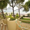 Un balcone con tavolino, sedie, stendino e vista mare, circondato da pini.
