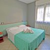 Stanza con letto matrimoniale, copriletto azzurro, finestra con tenda, e mobili coordinati.