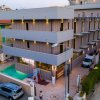 Hotel moderno con piscina e auto parcheggiate davanti.