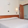 Camera con letto matrimoniale, due applique accese e porta aperta.