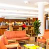 Lounge bar con divani arancioni, tre persone al bancone, pianta decorativa.