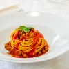 Un piatto di spaghetti con salsa di pomodoro, ceci e foglie di basilico fresco.