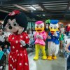 Persone in costume da personaggi animati camminano tra la folla in un evento al coperto.