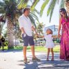 Famiglia che passeggia tra le palme, sorridendo.