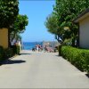 Viale alberato che conduce al mare, con biciclette parcheggiate vicino al cancello.