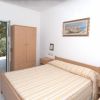 Stanza da letto con letto matrimoniale, armadio in legno, e porta aperta verso un balcone.