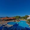 Piscina con ombrelloni blu e vista sul mare.