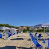 Lettini e ombrelloni blu su spiaggia soleggiata.