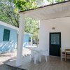 Veranda con tavolo e sedie bianche accanto a un edificio blu.