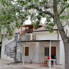 Casa bianca a due piani con scala esterna e tavolo sotto gli alberi.